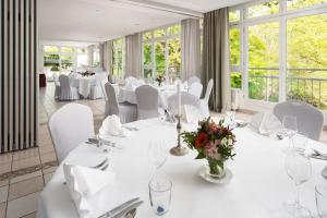 a dining room with white tables and chairs and windows at Kleinhuis Hotel Mellingburger Schleuse in Hamburg