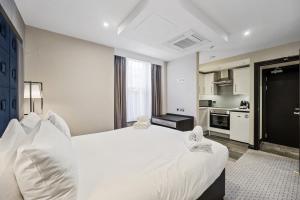 a bedroom with a large white bed and a kitchen at The Westbourne Residences in London