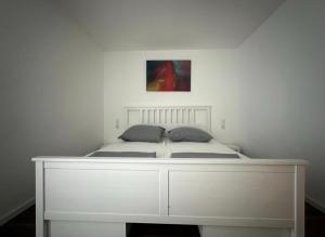 Ein weißes Bett in einem Schlafzimmer mit einem Gemälde an der Wand in der Unterkunft Apart Halver in Halver