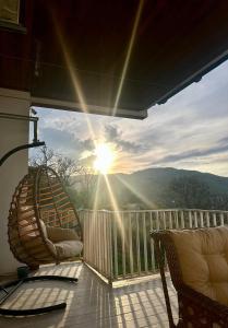 a balcony with two chairs and the sun shining at Gudaleti Palace Private Countryside Villa near Tbilisi in Kaspi
