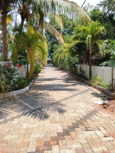 a brick pathway with palm trees in a garden at Krisna vykundam in Guruvāyūr