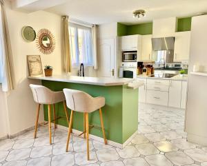 a kitchen with green and white counters and stools at Maison Bellebat - proche d'Orleans in Orléans