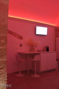 a pink room with a table and two stools at Dofely Suites - Tritone in Polignano a Mare