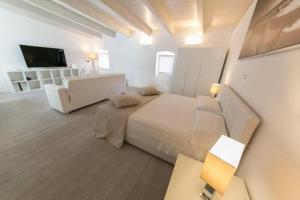 a white bedroom with a bed and a television at Primo Piano in Sparano in Bari