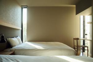 a bedroom with two beds and a chair and a window at Hiire IZU OLIVE in Ito