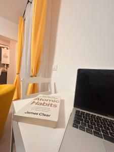 a book sitting on a table next to a laptop computer at Yellow Dawn Modern Flat in Quiet Area with Garage Parking and Self Check-In in Rediu