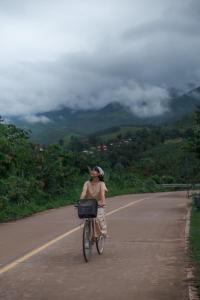 a woman riding a bike down a road at สะปันดีวิว Sapan Dee View บ่อเกลือ น่าน in Ban Huai Ti