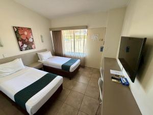 a hotel room with two beds and a television at Ashwood Motel in Gosford