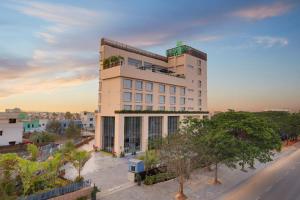 a tall white building with trees in front of a street at Lemon Tree Hotel, Bhubaneswar in Bhubaneshwar
