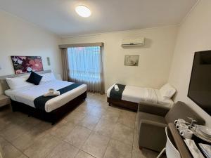 a hotel room with two beds and a television at Ashwood Motel in Gosford +33 photos