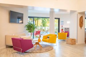 a living room with colorful chairs and a table at Hôtel Le Bayonne in Bayonne