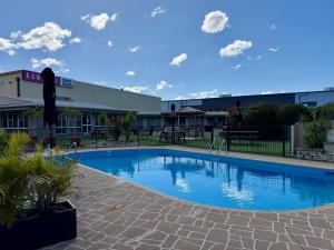 a large swimming pool in front of a building at Ashwood Motel in Gosford