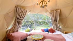 a room with two beds in a tent with a window at Yufuin Glamping COMOREBI in Yufu