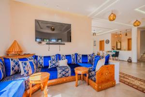 a living room with a blue couch and chairs at Villa moderne à 5 min de la plage avec jardin et 3 salons in Essaouira