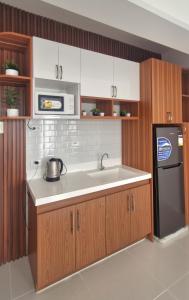 a kitchen with a sink and a black refrigerator at The Crib at Royal Oceancrest Mactan in Lapu Lapu City