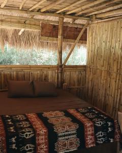 a room with a bed in a straw hut at Betelnut Eco-Lodge Sumba in Lambatama