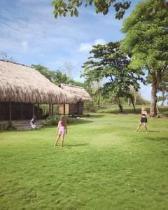 two children playing frisbee in the grass in front of a hut at Betelnut Eco-Lodge Sumba in Lambatama