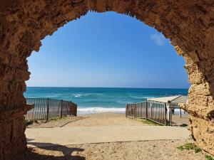 a view of the beach through a stone archway at The Caesar Stay in Caesarea