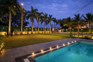 a backyard with a swimming pool and palm trees at night at Amber Resort & Spa in Indore