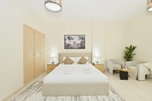 a white bedroom with a bed and a couch at Bloomfields Studio Emirates Cluster 24 Intl. City in Dubai