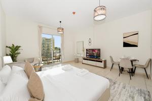 a white bedroom with a white bed and a table at Bloomfields Studio Emirates Cluster 24 Intl. City in Dubai