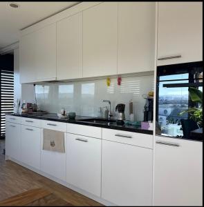 a white kitchen with white cabinets and a sink at Room with an amazing city view in Basel