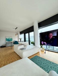 a living room with a white couch and a large tv at Room with an amazing city view in Basel