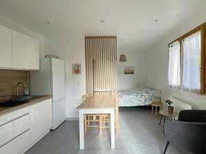 a kitchen with a table and a room with a bed at Studio au calme - rez de jardin in Chignin