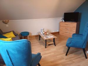 a living room with blue chairs and a table at Les Puits Bessin Normandie in Sommervieu