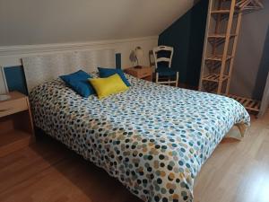 a bedroom with a bed with blue and yellow pillows at Les Puits Bessin Normandie in Sommervieu