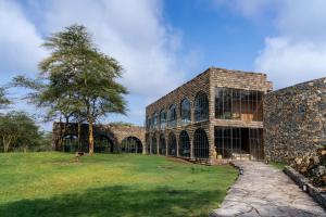 a large stone building with a tree in front of it at Giraffe Manor Tanzania in Usa