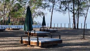 a group of picnic tables with umbrellas on the beach at Brio de Agoho Zambales by Cherry in Candelaria +3 photos