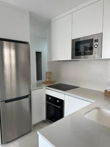 a kitchen with white cabinets and a stainless steel refrigerator at Prestige Sunny Terrace Apartment - Torrevieja in Torrevieja