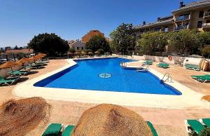 a large swimming pool with chairs and a building at Blue Piscis Studio - Piscina in Benalmádena