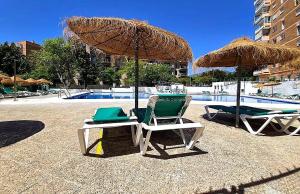 two chairs and an umbrella next to a pool at Blue Piscis Studio - Piscina in Benalmádena