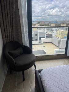 a bedroom with a chair and a large window at Kozy studio near JKIA Nairobi, Free parking fast WiFi,Kingsize bed,no card in Nairobi