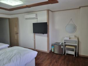 a bedroom with a bed and a tv on the wall at Orasung Motel in Jeju