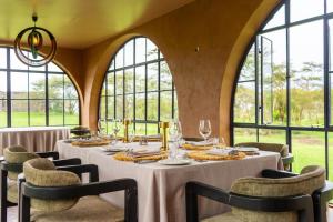 a dining room with a table with chairs and windows at Giraffe Manor Tanzania in Usa +28 photos