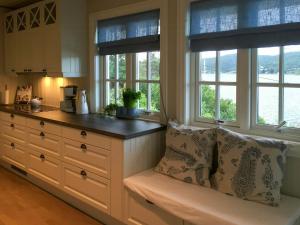 a kitchen with windows and a bench with pillows at Cottage With Private Dock By Eidangerfjord in Porsgrunn
