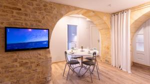a dining room with a table and a tv on a stone wall at Hôtel des Récollets in Sarlat-la-Canéda