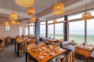 a restaurant with tables and chairs and large windows at Zostel Guwahati in Guwahati