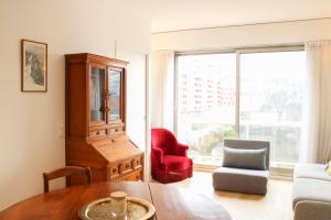 a living room with a table and a red chair at Renovated studio with quiet balcony in Bois-Colombes