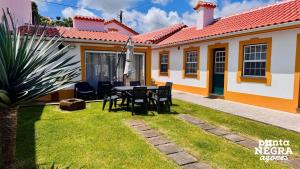 a patio with a table and chairs in front of a house at Alojamento Ponta Negra in Biscoitos