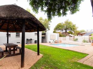 a picnic table and an umbrella next to a pool at Andela Guesthouse in Bloemfontein