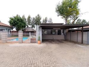 a house with a gate and a fence with a pool at Andela Guesthouse in Bloemfontein +7 photos