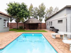a swimming pool in a yard with a gazebo at Andela Guesthouse in Bloemfontein