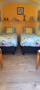 two beds in a room with wooden floors at Pipowagen in Grashoek