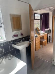 a bathroom with a sink and a kitchen with a desk at Camaraderie Guest House in York +31 photos