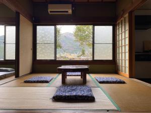 a room with mats around a table and windows at Hostel Kumano Kodo in Tanabe +34 photos