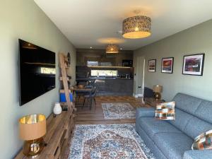 a living room with a couch and a dining room at Cadderlie Cabin - Luxury Woodland Escape with Hot Tub Near Oban in Oban